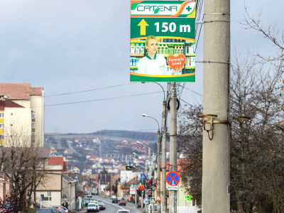Panou direcțional amplasat pe stâlpul de illuminat public.