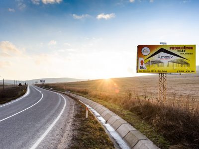 Panou publicitar tip unisign amplasat pe marginea drumului în timpul zilei